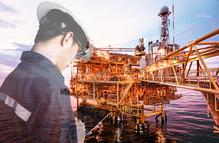 Worker on oil rig platform using digital communication equipment